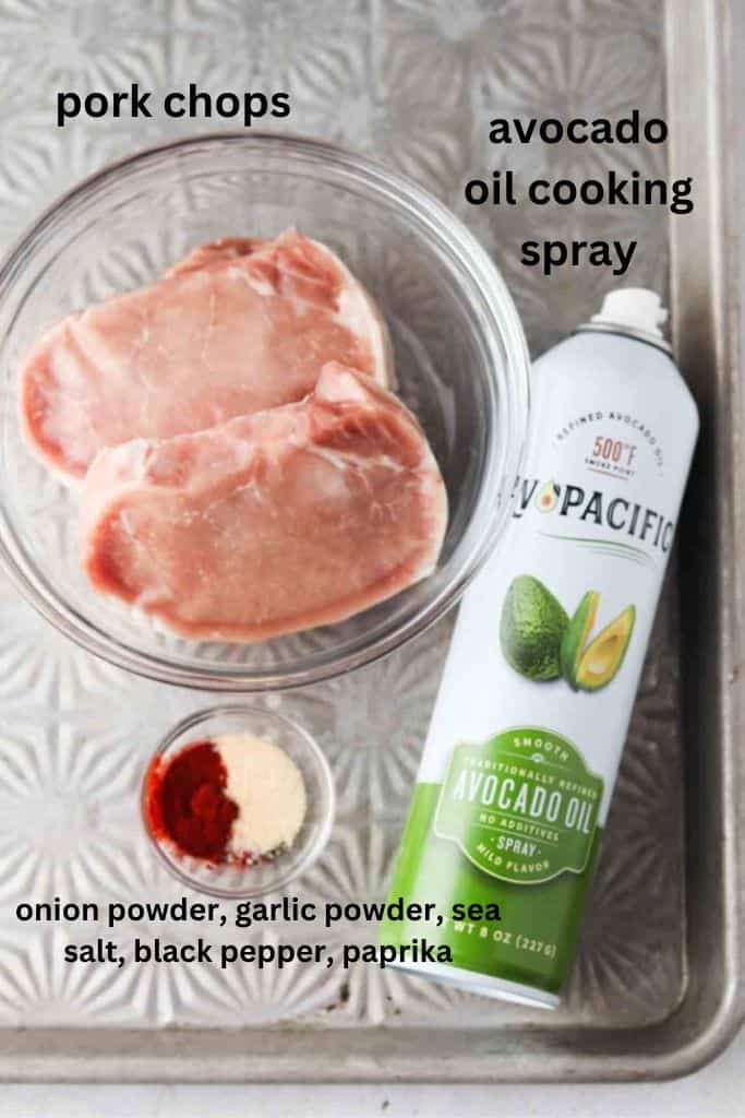 Frozen pork chops in the air fryer ingredients on a silver baking sheet in small glass bowls.