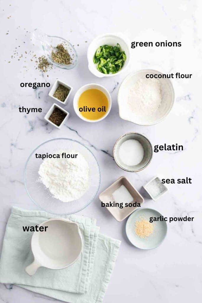Aip bread roll ingredients in small bowls on a marble back drop.