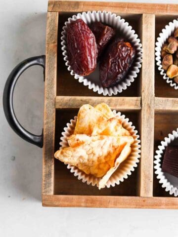 Snacks in a snack platter with dates, nuts and treats in cup cake liners.
