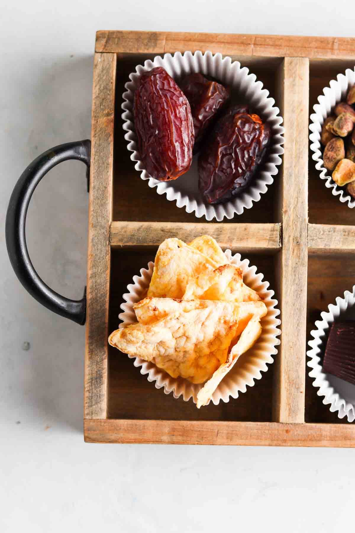 Dairy and gluten free snacks on a snack board in cupcake liners. 