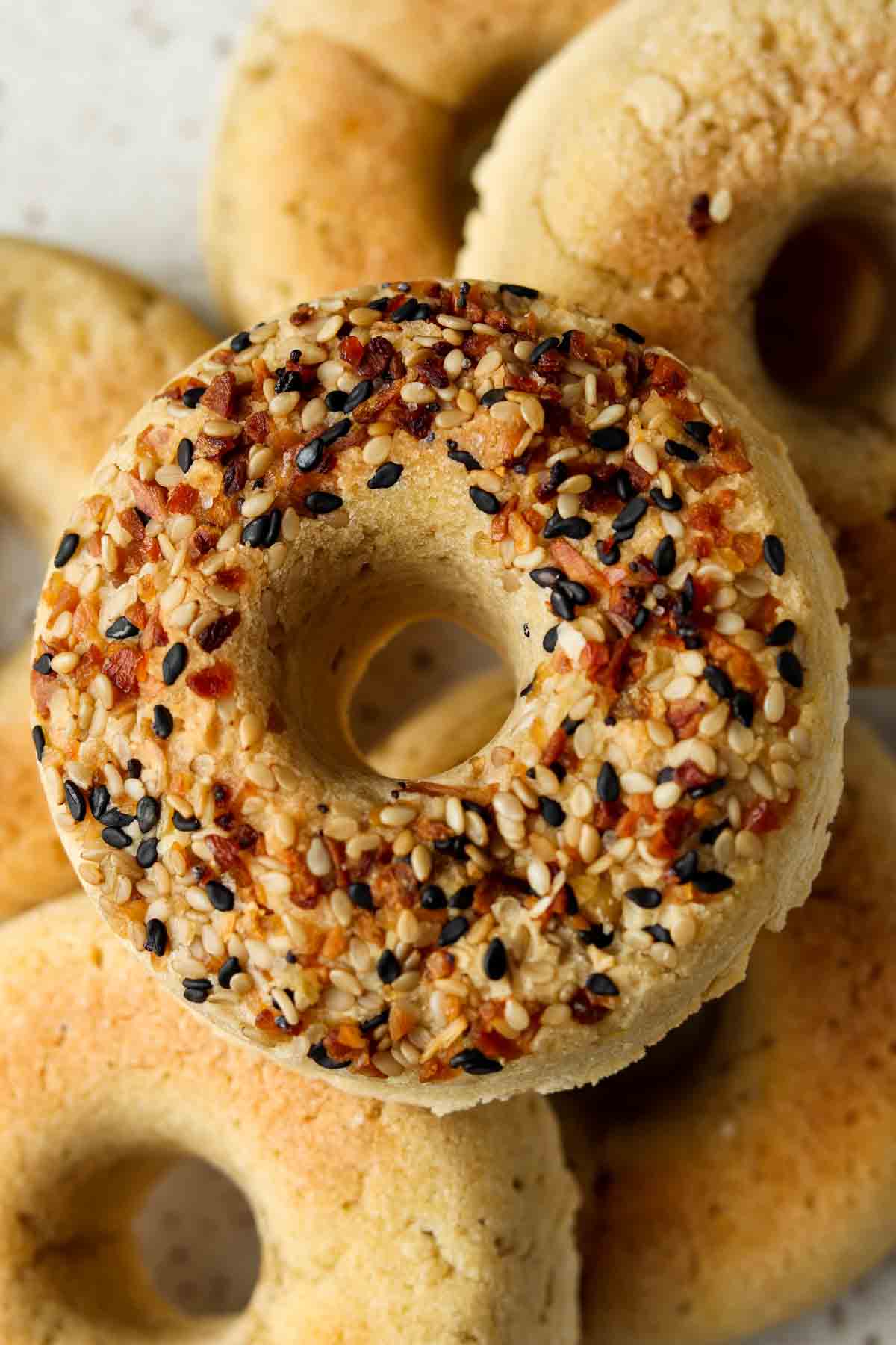 Gluten free bagels stacked on a plate with everything bagel seasoning on top.