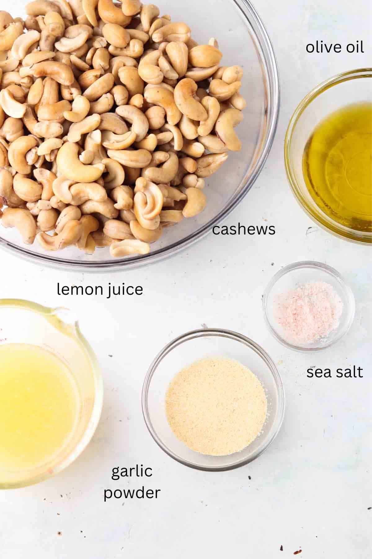 Cashew cheese ingredients laid out in small glass bowls on a counter top.