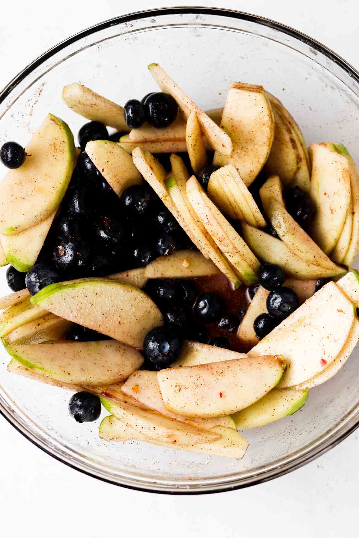 Apples and blueberries tossed with spices and arrowroot in a bowl.