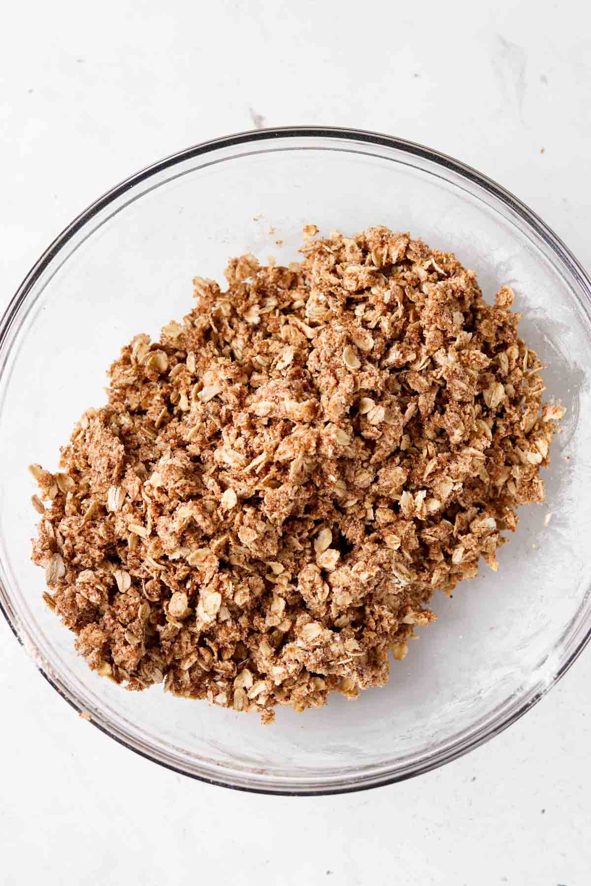 Oat crumble topping in a glass bowl with ghee mixed in. 