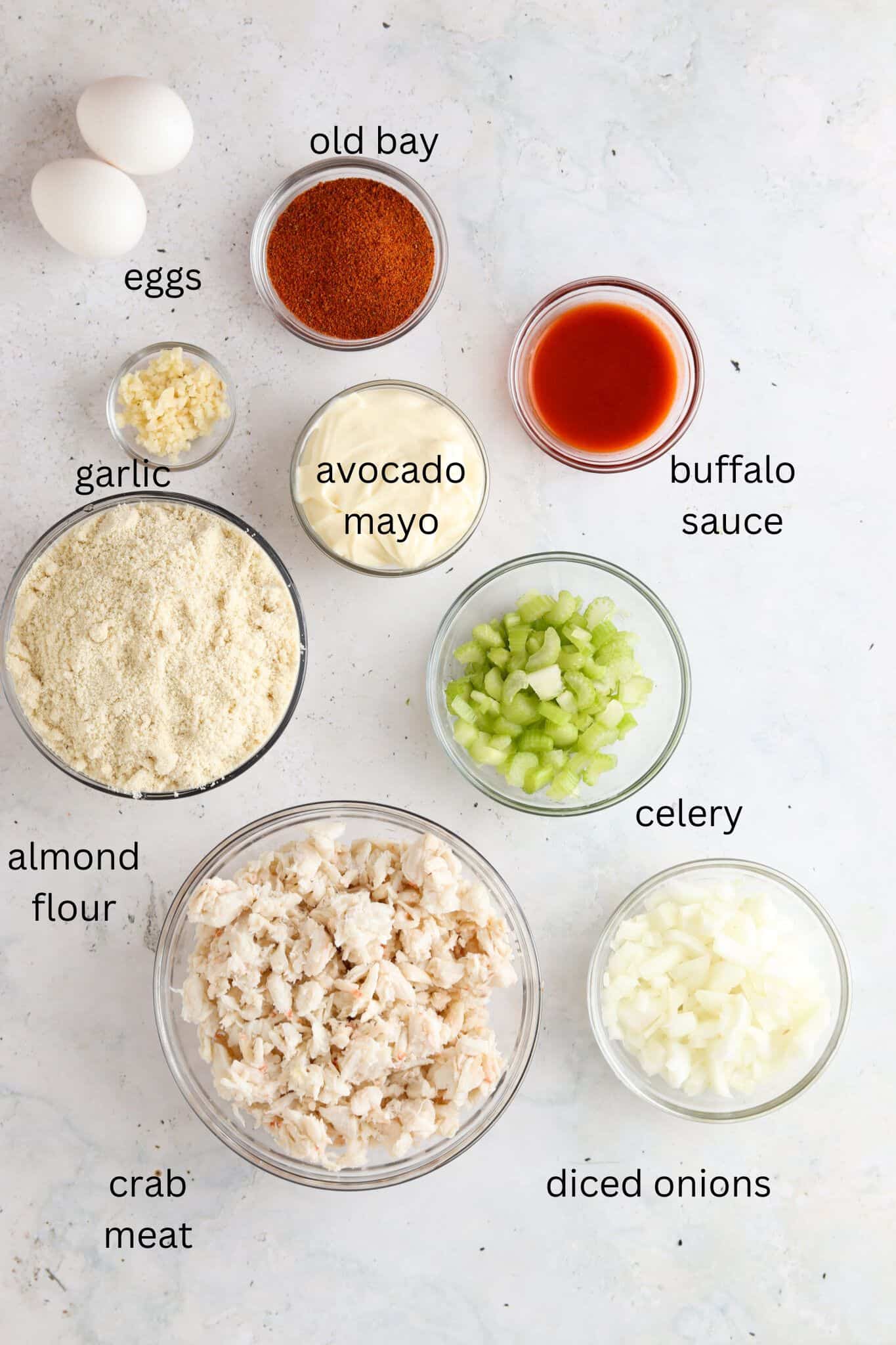 Crab cake ingredients laid out in small glass bowls on the counter. 