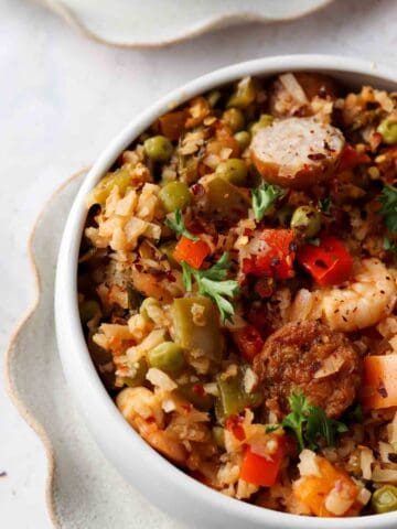 Paella in a small bowl with fresh herbs sprinkled on top.