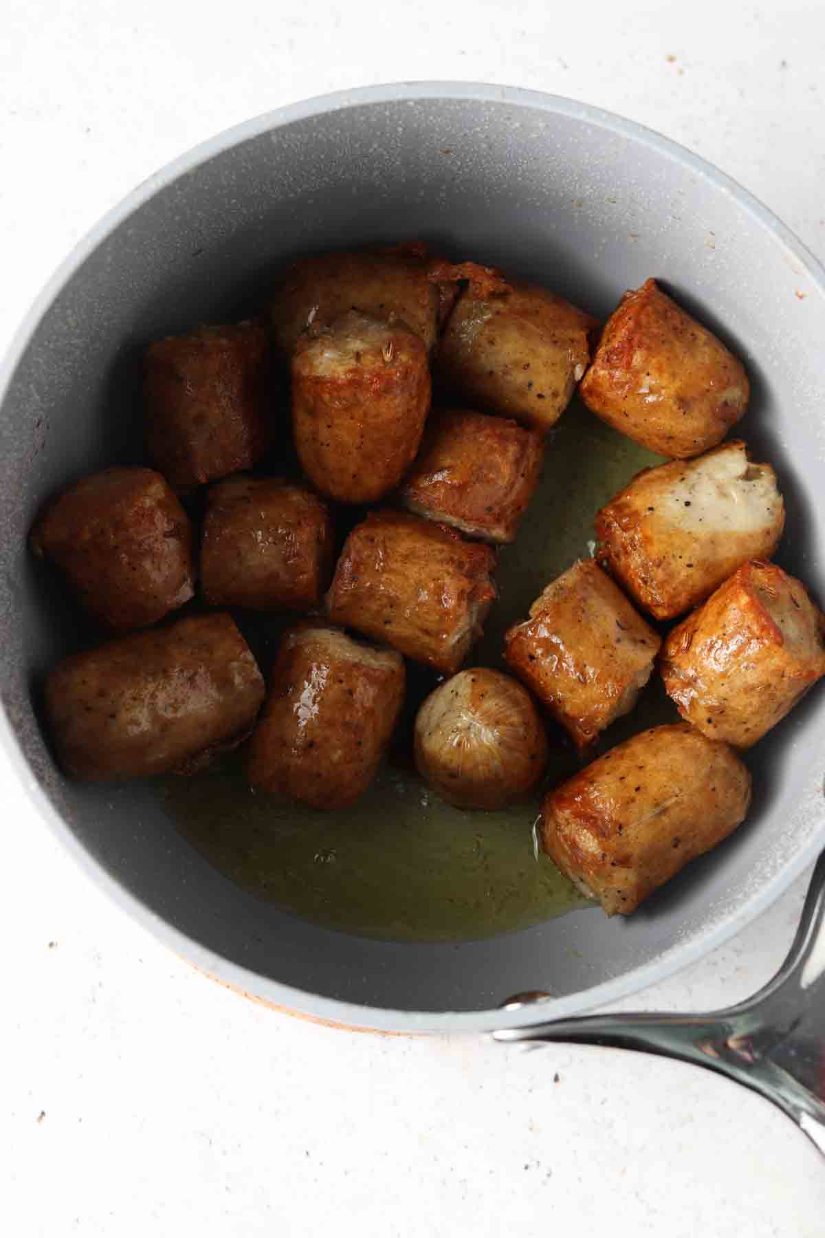 Ghee in a saute pan with chopped up sausage. 