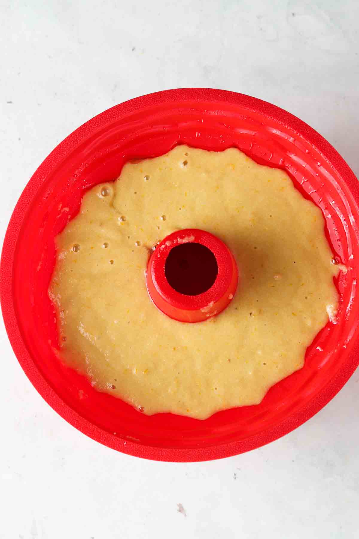 Cake mixture in a red silicone bundt pan.