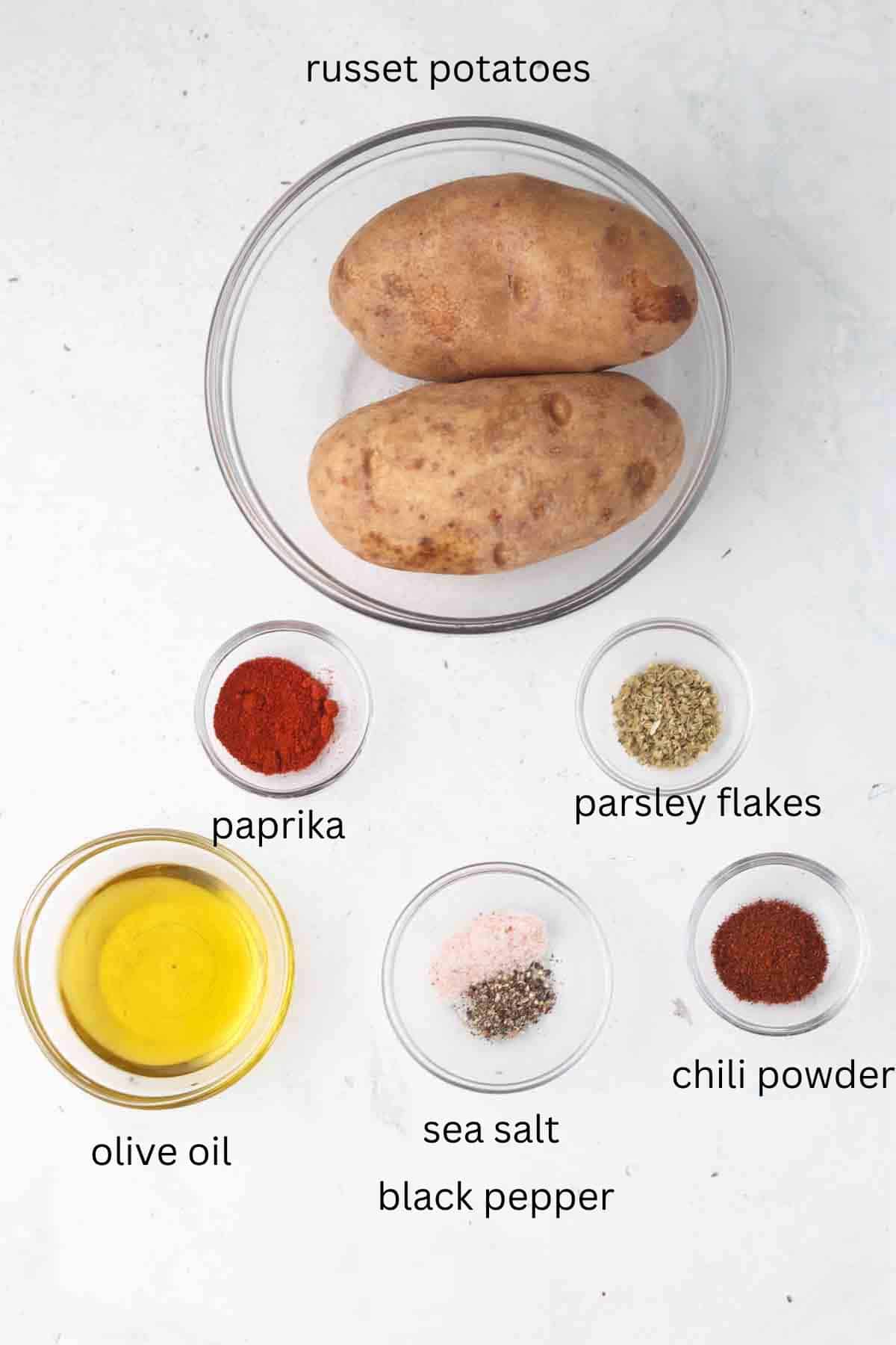 Ingredients for air fryer potatoes in glass bowls on a table.