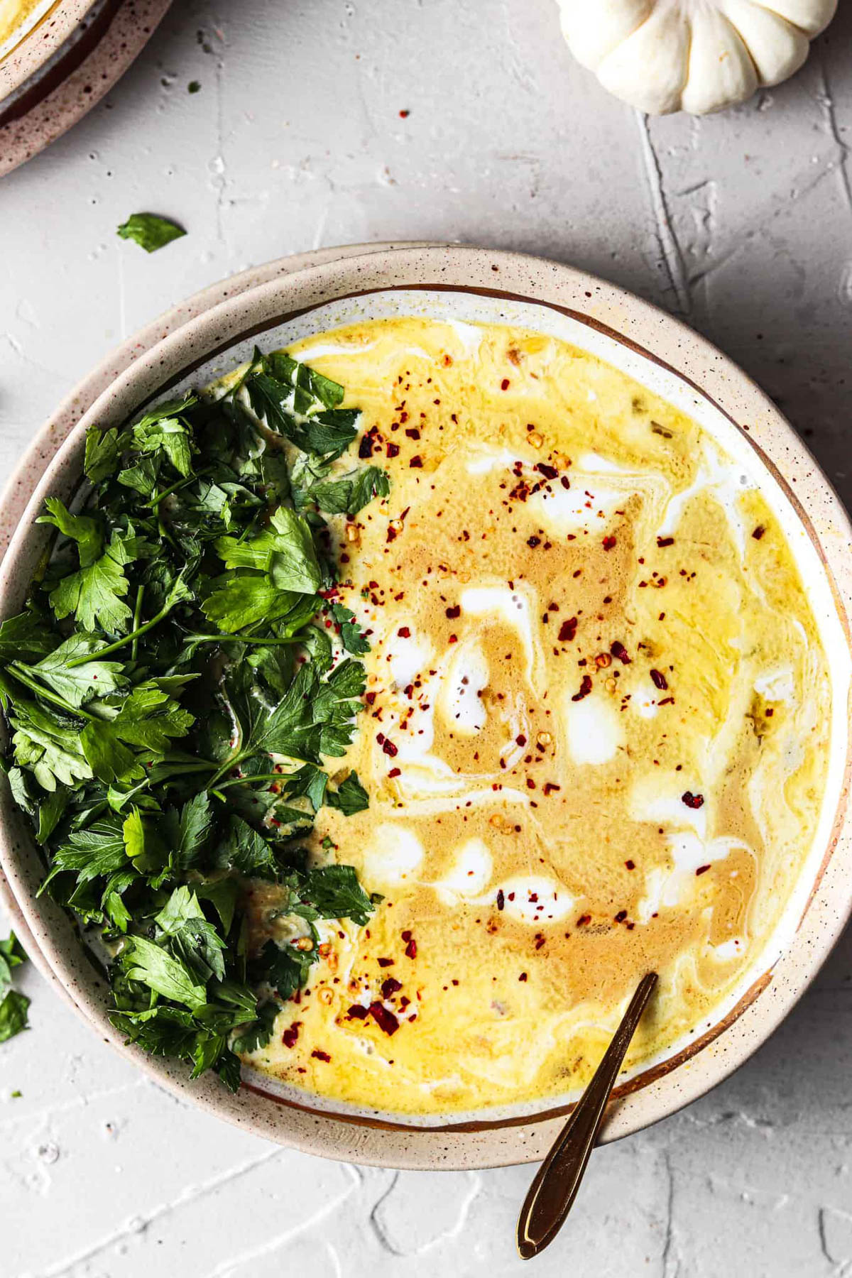 Almond Butter Chicken Pumpkin in a bowl with fresh green herbs. 