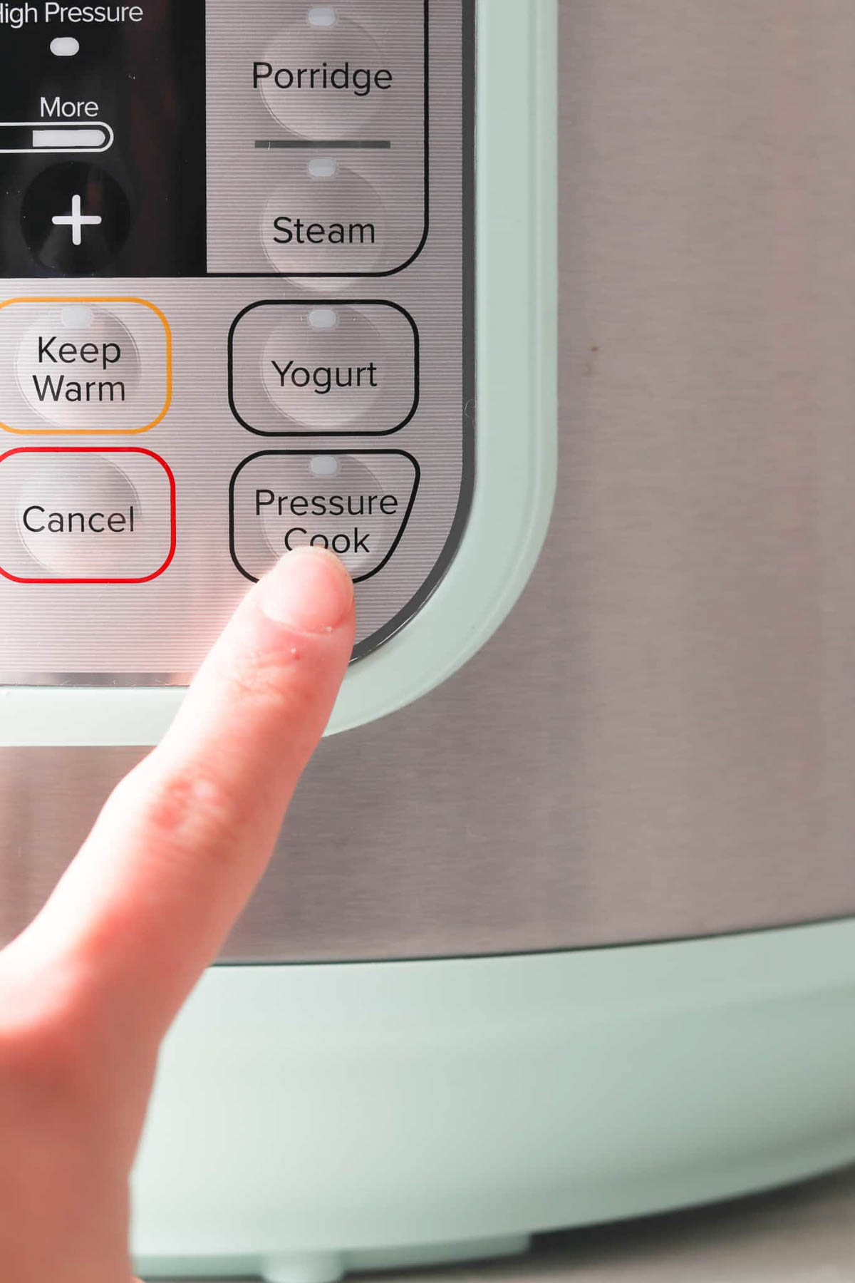 Front of an instant pot controls with a finger pressing pressure cook option. 