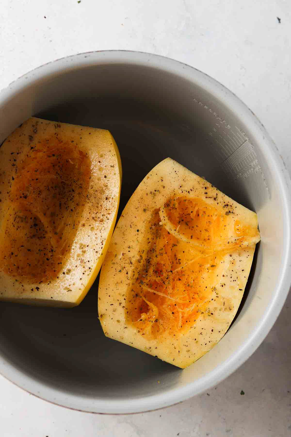 Sliced and seasoned spaghetti squash in an air fryer base.