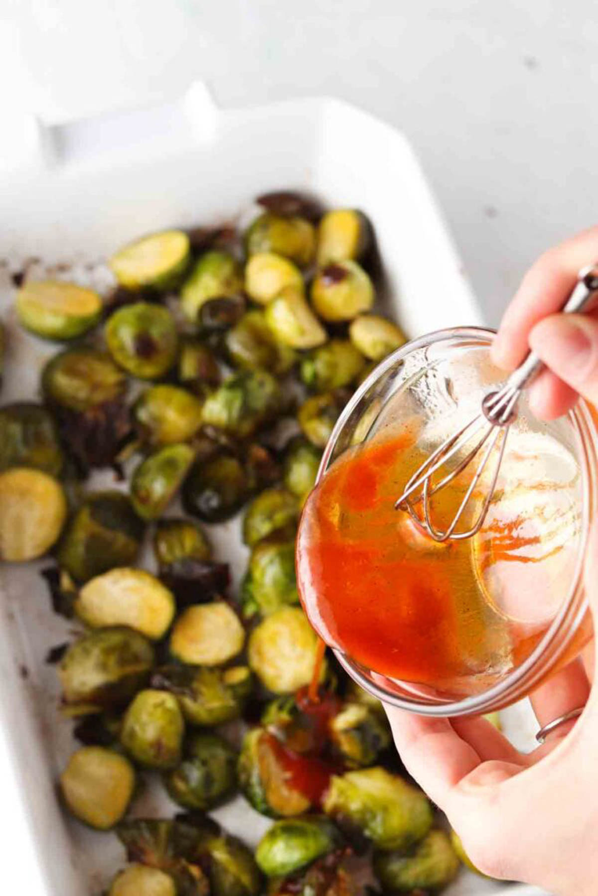 Uncooked brussel sprouts sliced in half in a casserole dish.