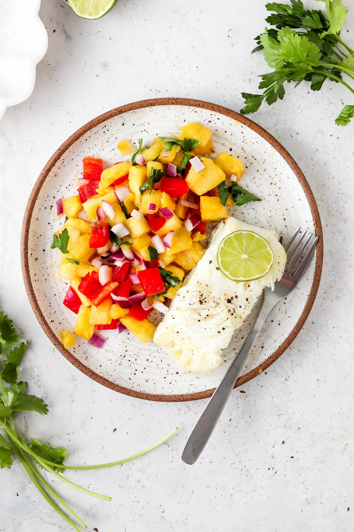 Pan seared sea bass with tropical pico de gallo on a plate with a fork.