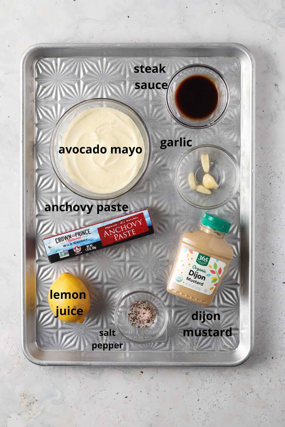 Whole30 caesar dressing ingredients on a silver metal tray.