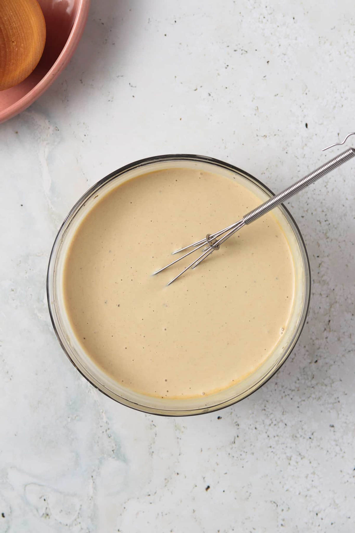 Whole 30 caesar dressing ingredients mixed together with a whisk in a small glass mixing bowl.