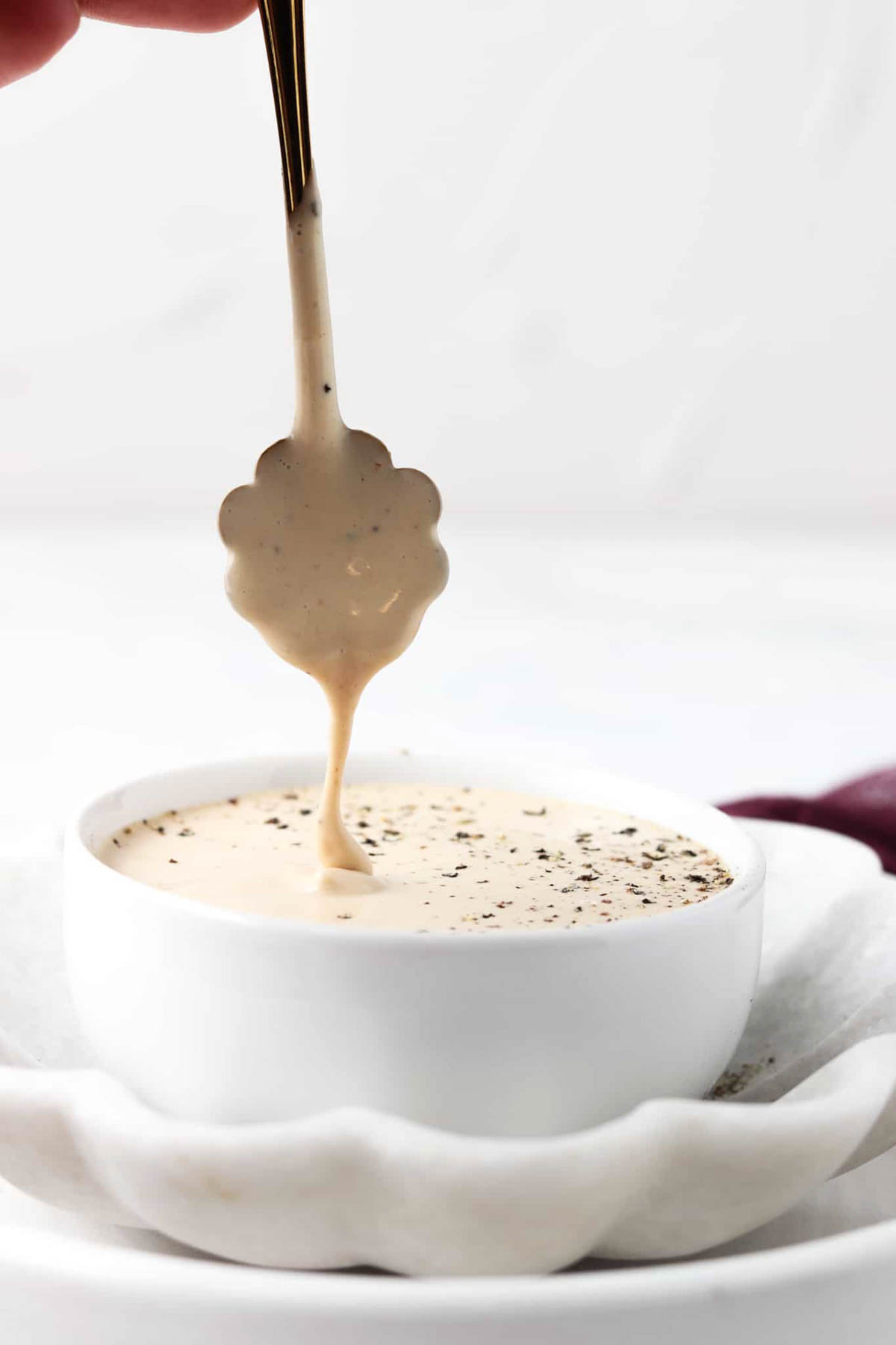 Whole30 caesar dressing with a spoon dripping into a bowl.