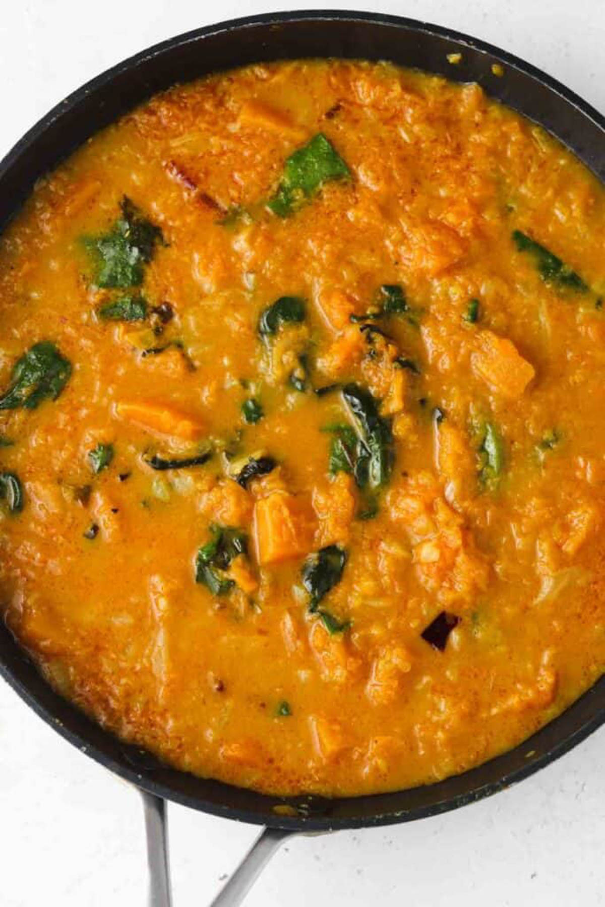 Cooking butternut squash curry simmering in a stock pan. 