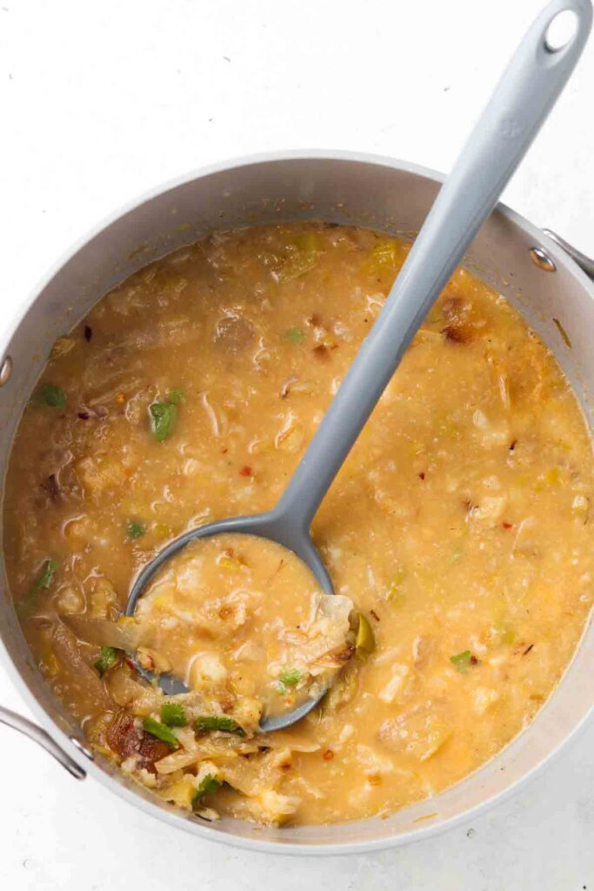 Cauliflower leek soup ingredients all in a stock pot with a ladle.