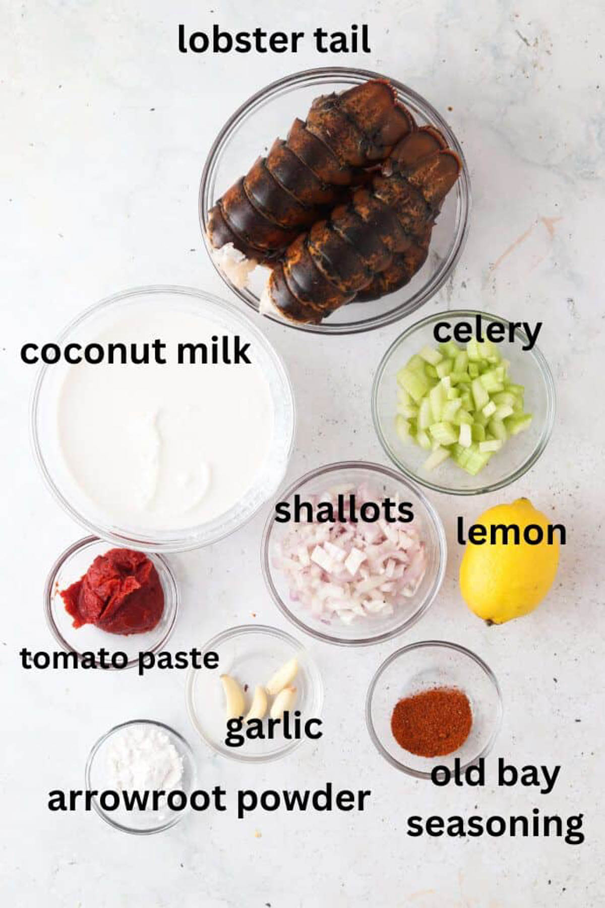 Dairy free lobster bisque ingredients in glass bowls on a marble background.