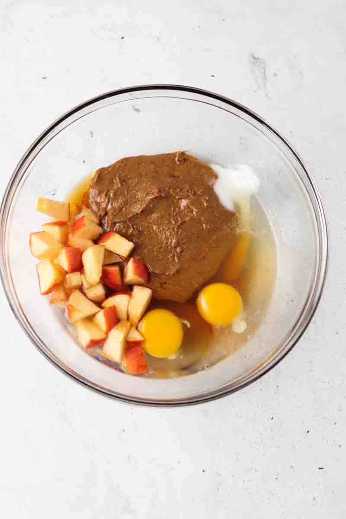 Gluten free apple muffin ingredients in a glass mixing bowl unmixed. 