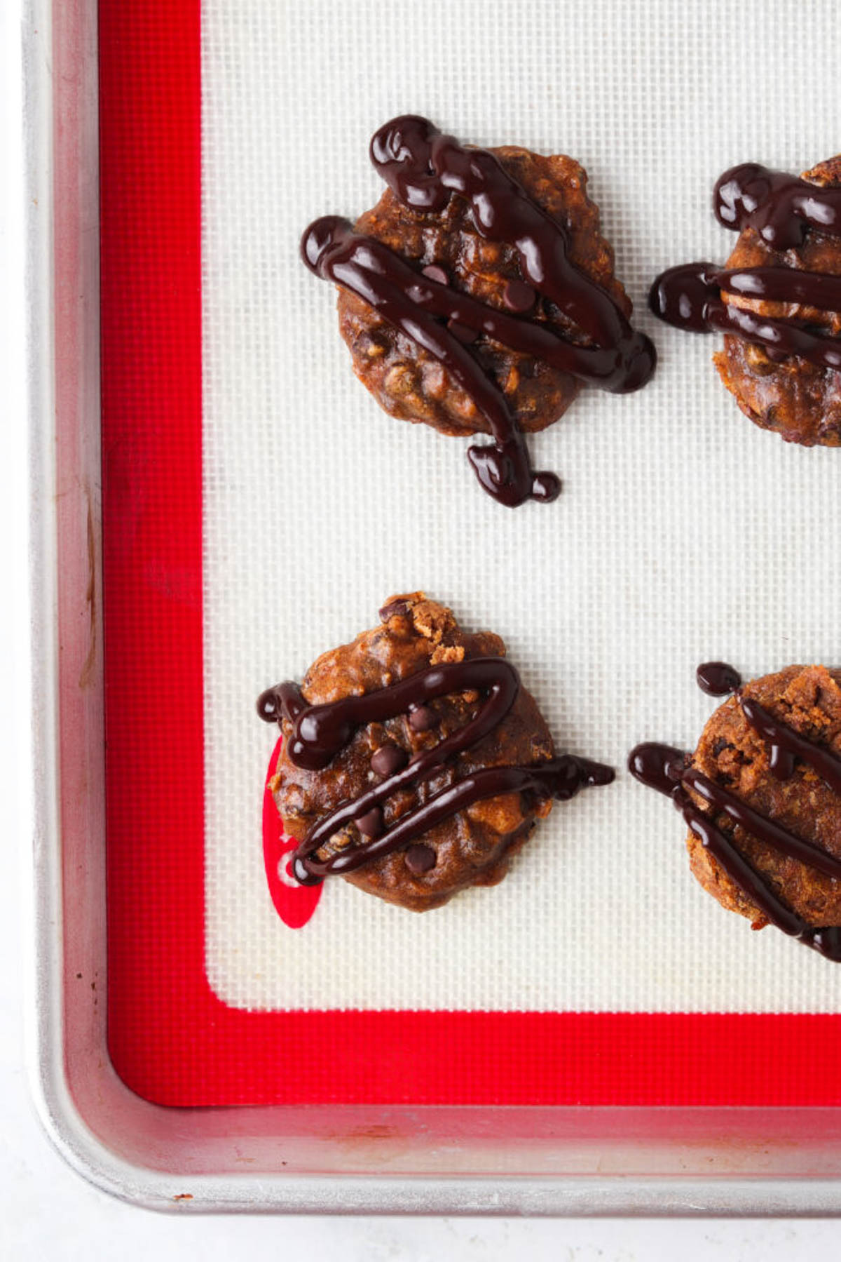 Gluten free pumpkin cookies on a baking sheet on a silicone parchment sheet.