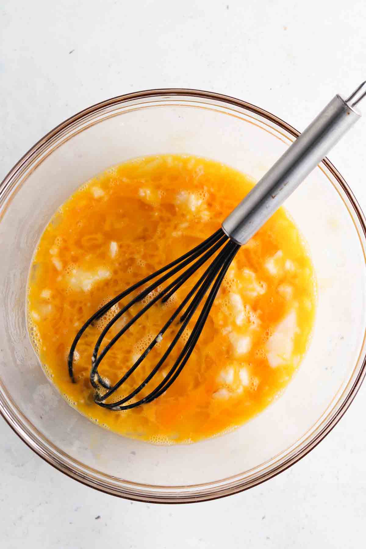 All wet ingredients mixed together in a large glass bowl with a whisk.