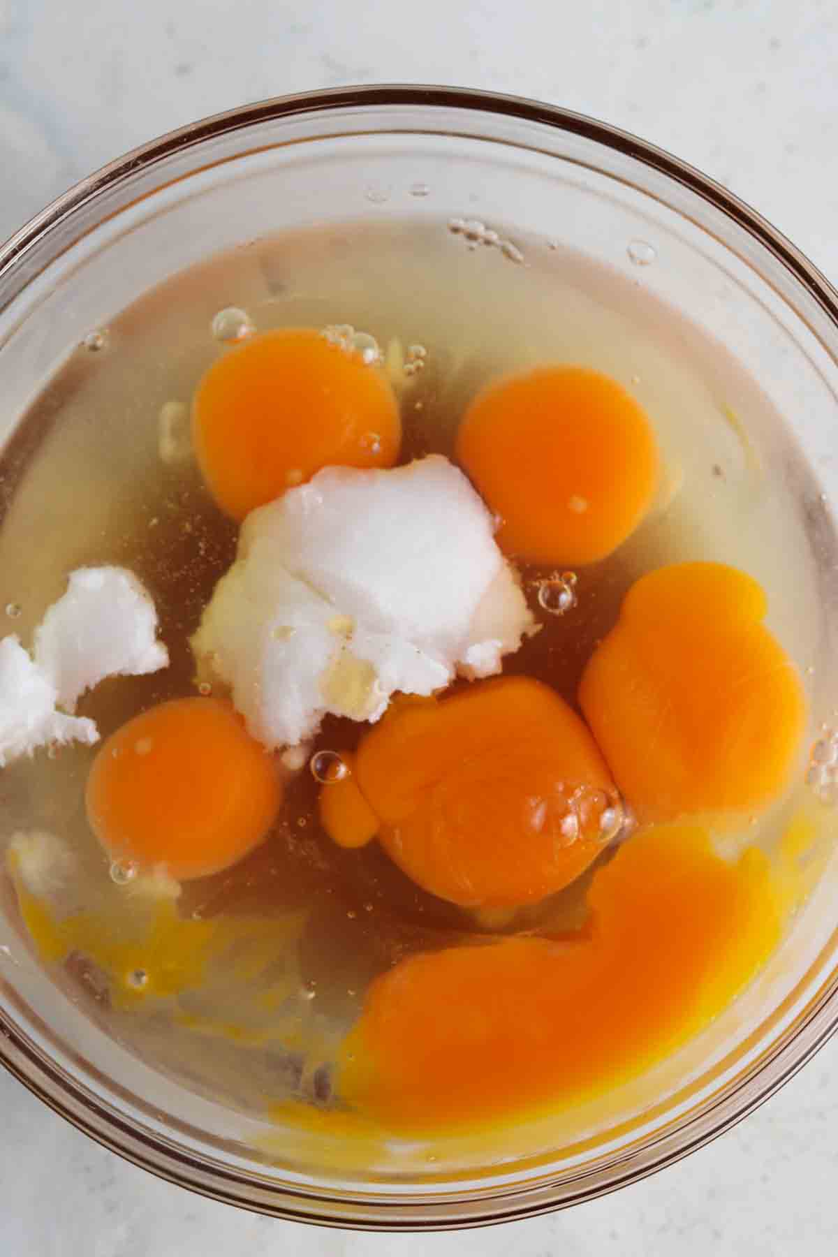 Egg, maple syrup, and coconut oil in a glass bowl.