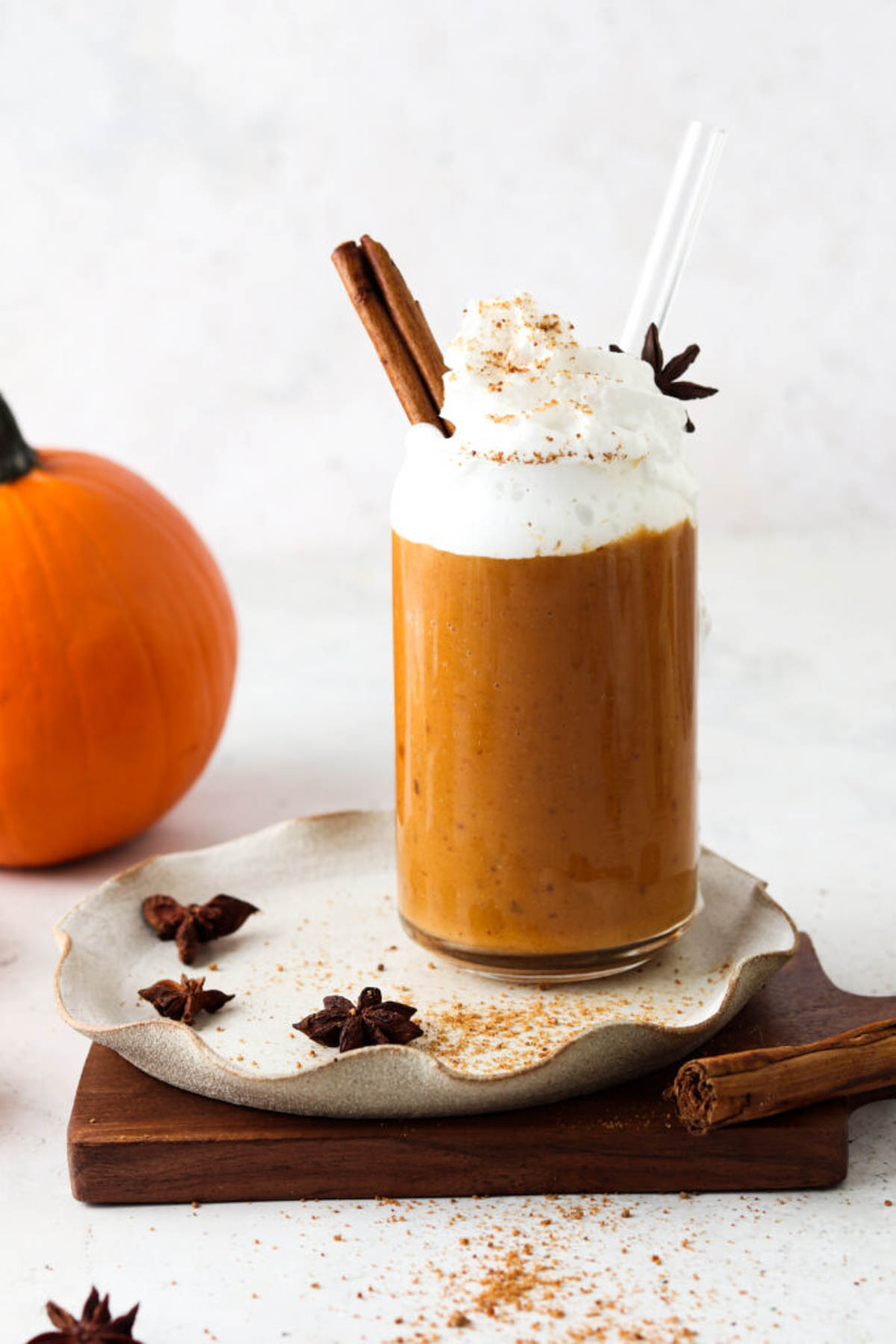 Dairy free pumpkin spice smoothie in a glass cup and topped with whipped cream and fresh spices.