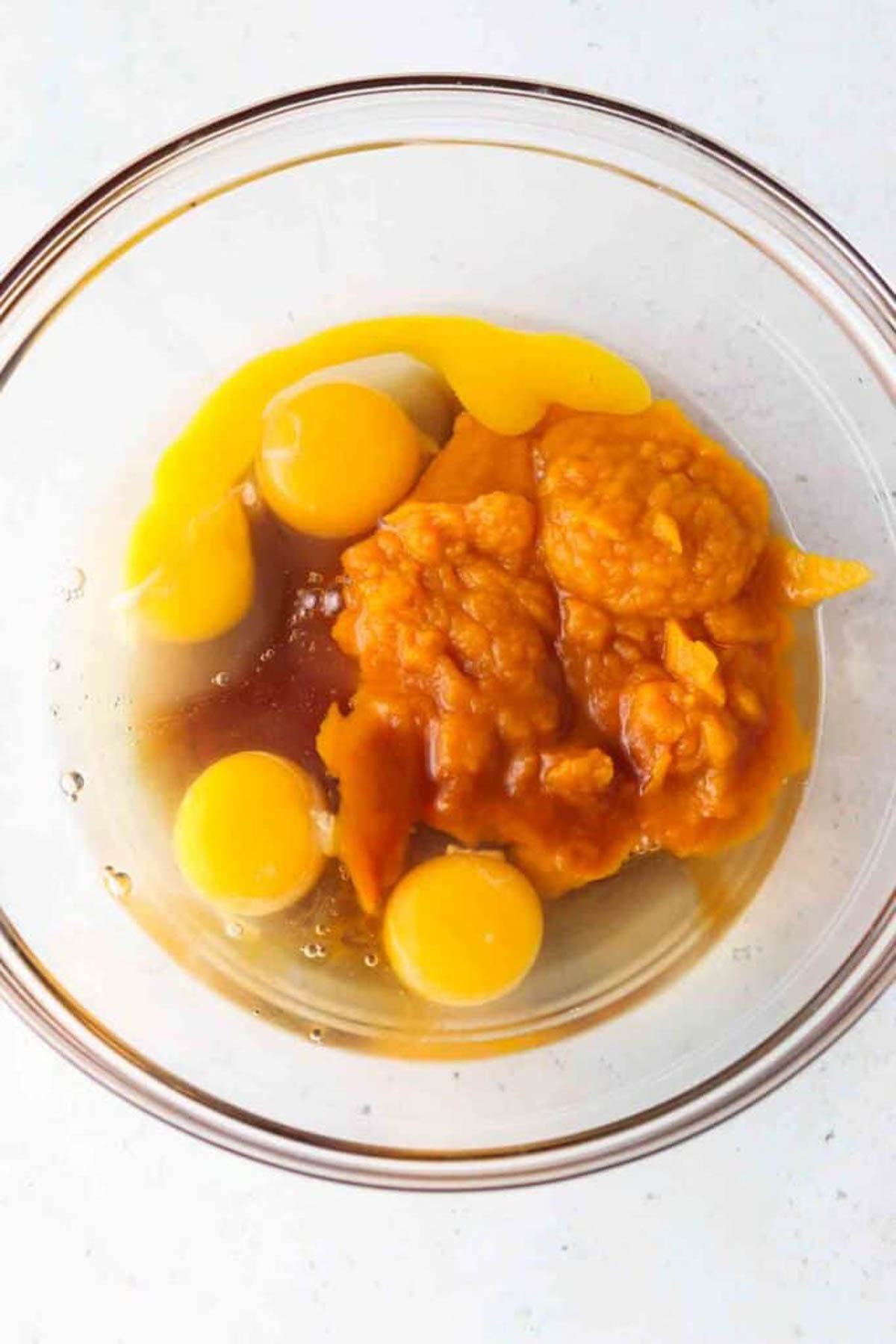 Gluten free pumpkin bread wet ingredients placed in glass mixing bowl separately.