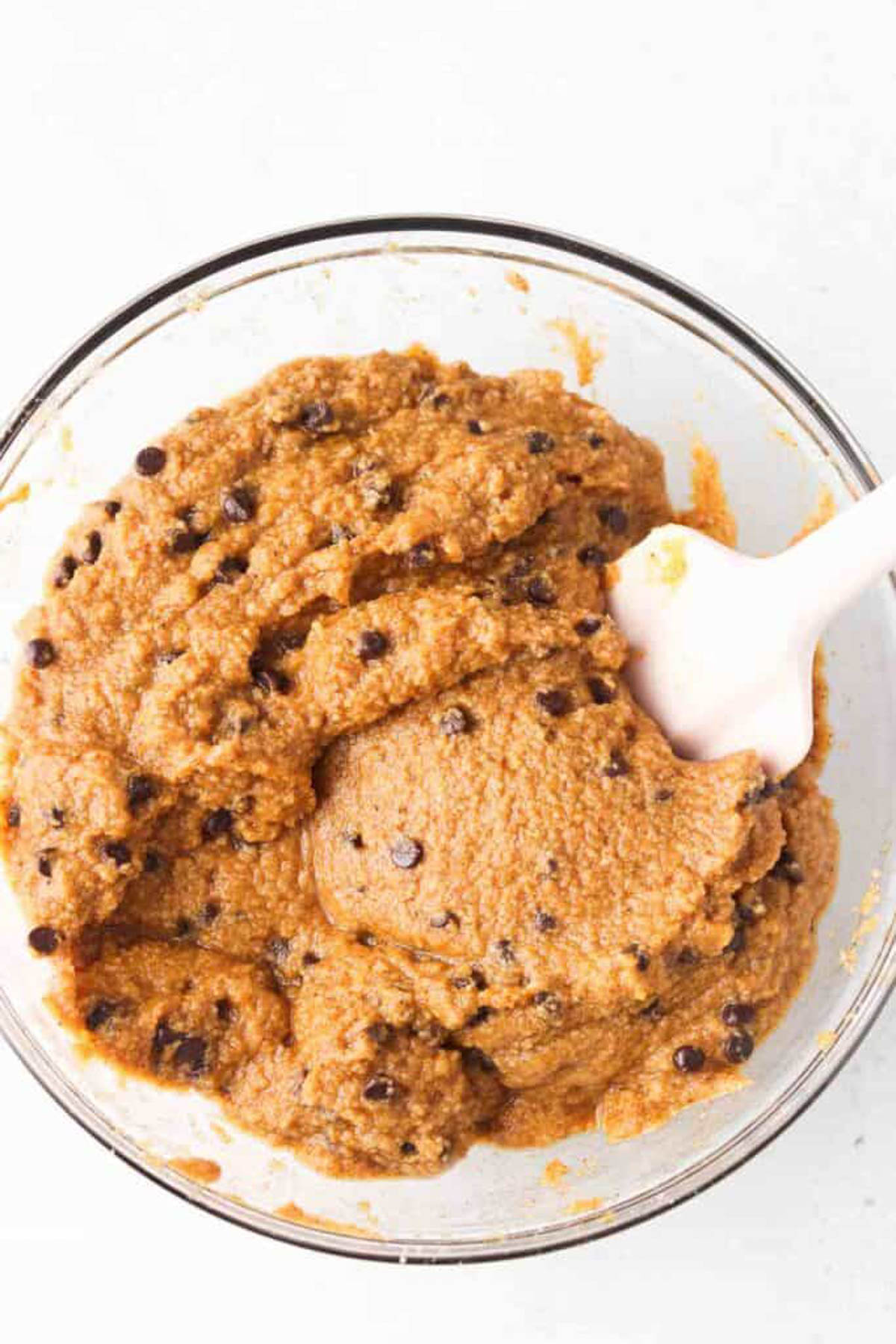 Gluten free pumpkin bread batter mixed together with dairy free chocolate chips in a glass mixing bowl.