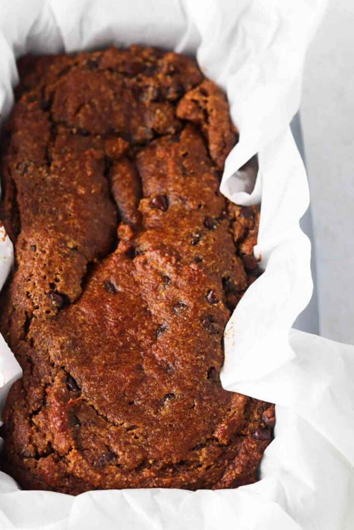 Gluten free pumpkin bread loaf in a pan with wax paper. 