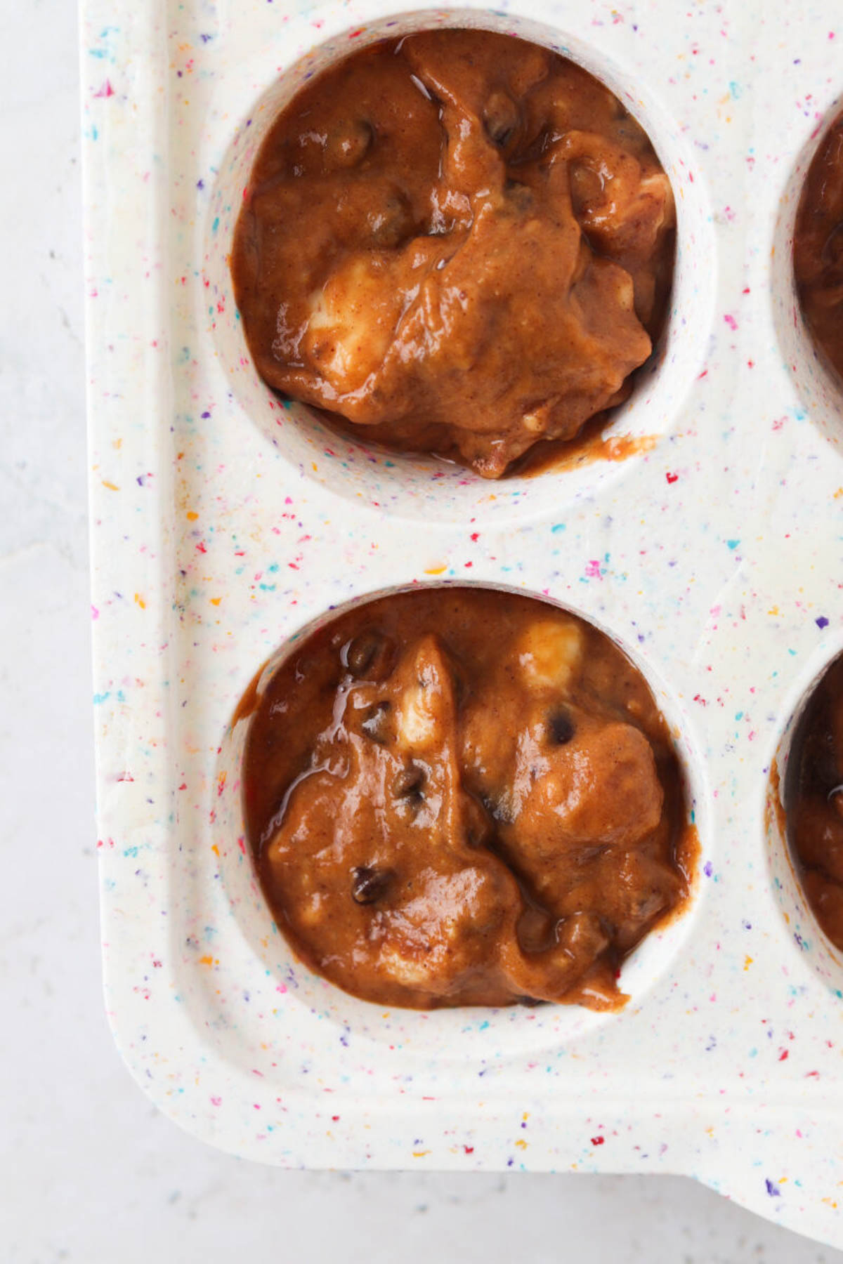 Raw gluten free pumpkin muffin batter in a silicone muffin pan.