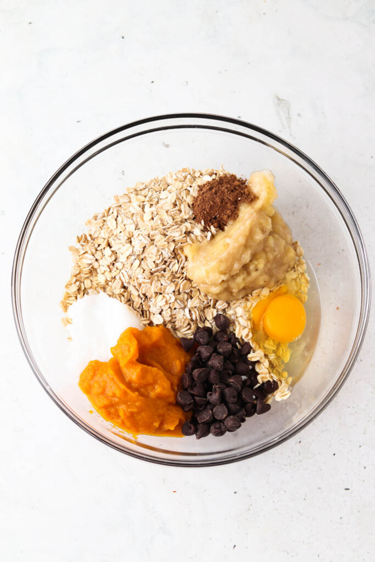 Pumpkin baked oatmeal ingredients in a glass mixing bowl unmixed.