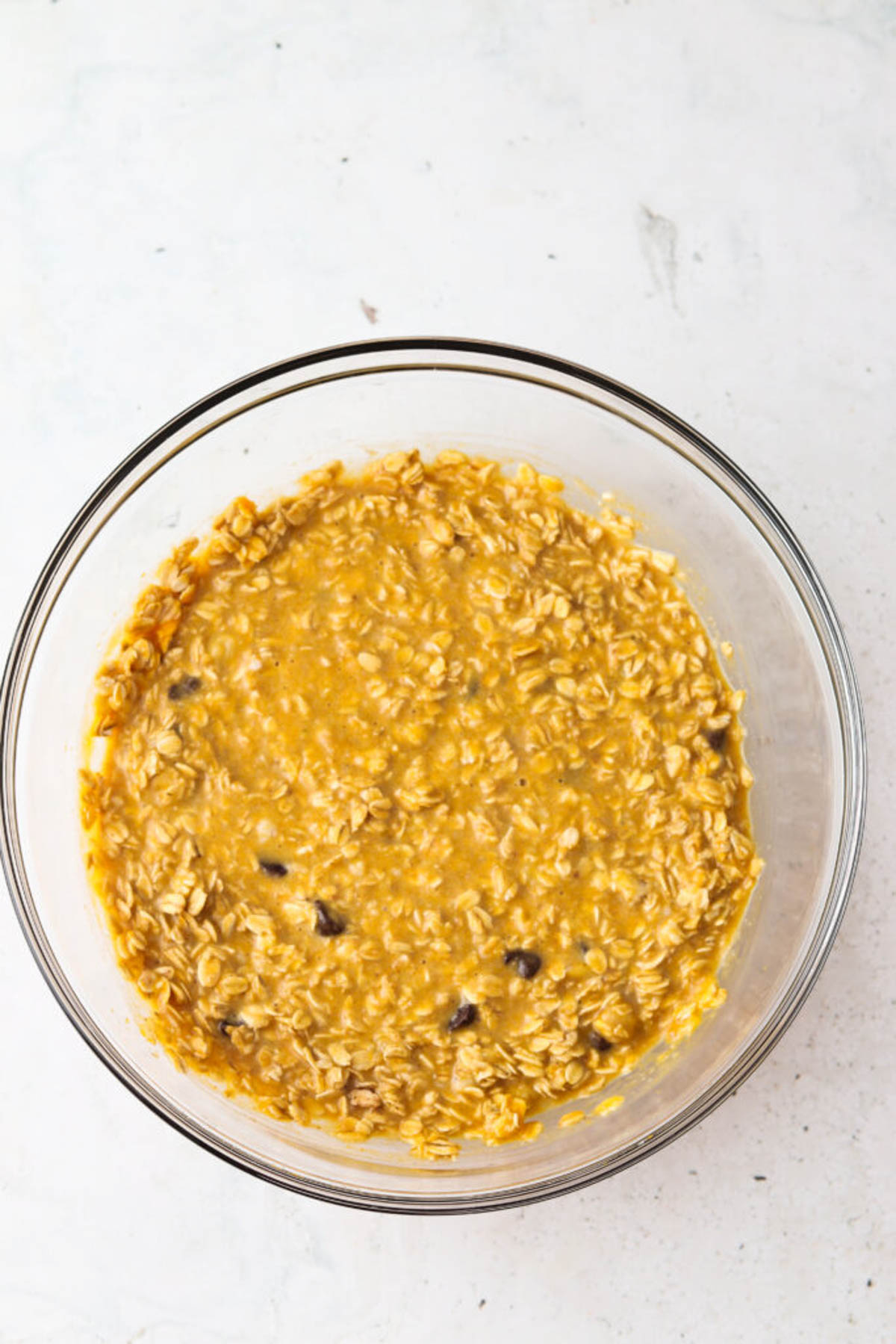 Raw pumpkin baked oatmeal batter mixed together in glass mixing bowl.