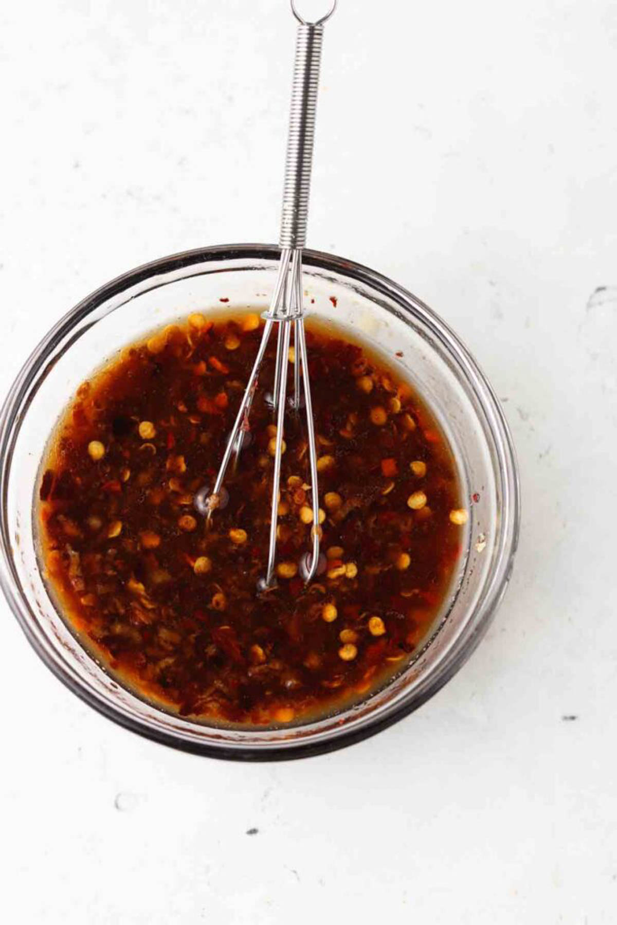 Roasted bok choy sauce in a glass bowl with a small whisk. 