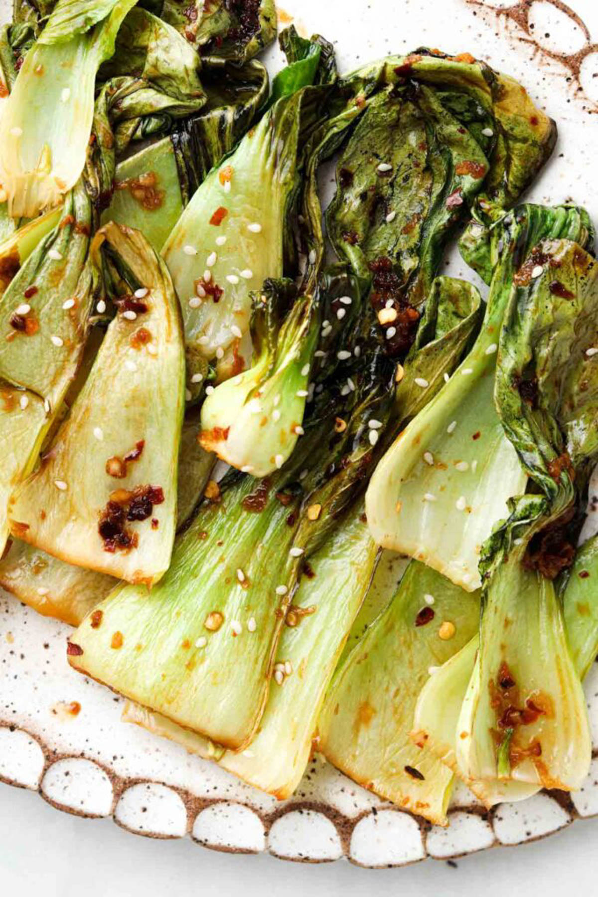 Roasted bok choy on a clay plate and garnished with sesame seeds. 