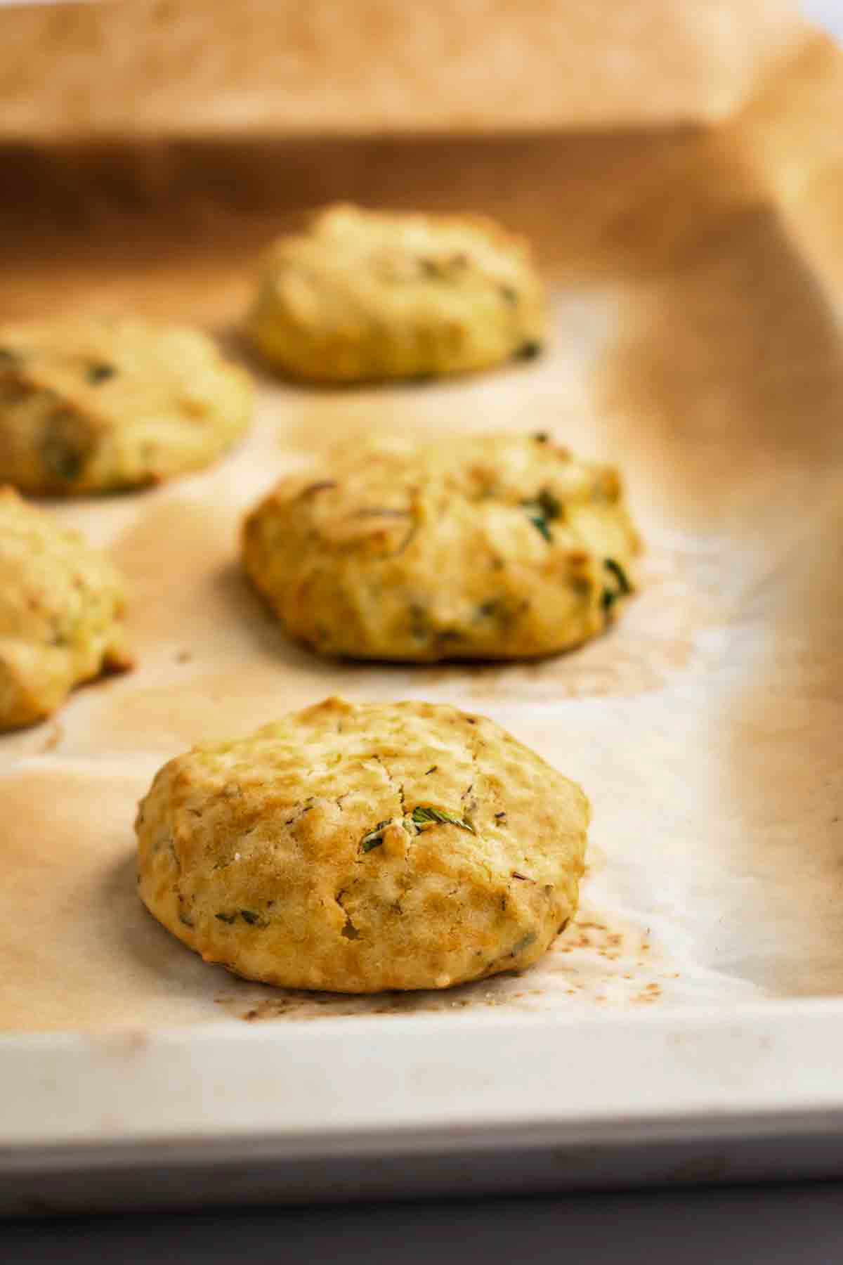 Baked aip bread rolls on parchment lined baking sheet.