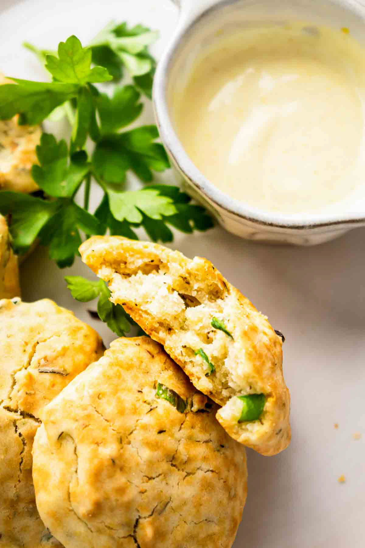 Aip bread rolls on a plate with fresh herbs and garlic butter.