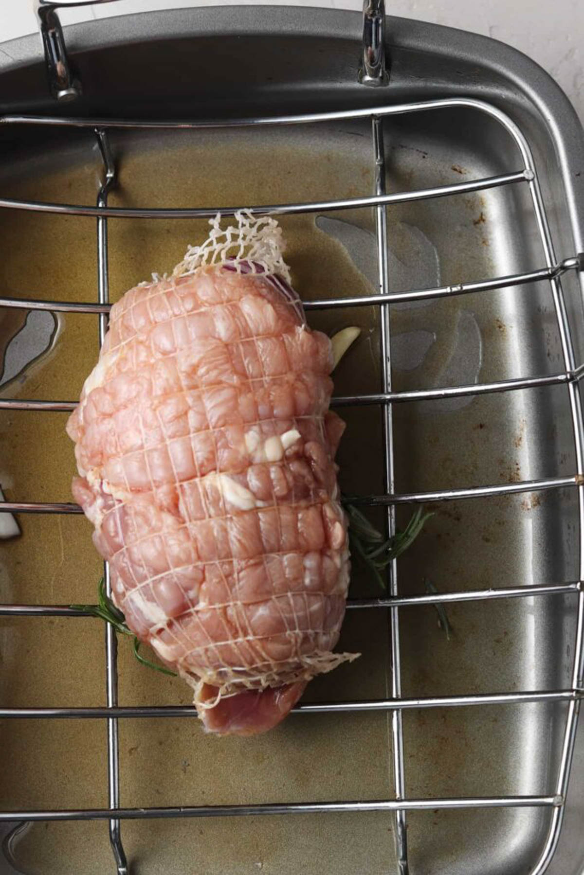 Partially roasted turkey breast in a roasting pan.