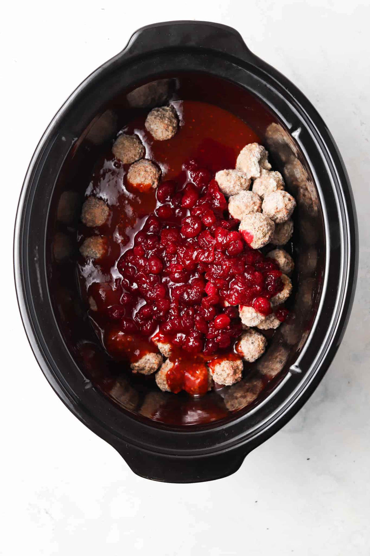 Cranberry BBQ meatball ingredients in a crockpot base unmixed.