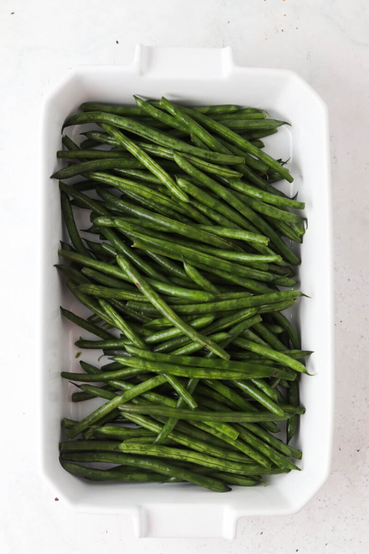 Green beans in a white casserole dish uncovered.