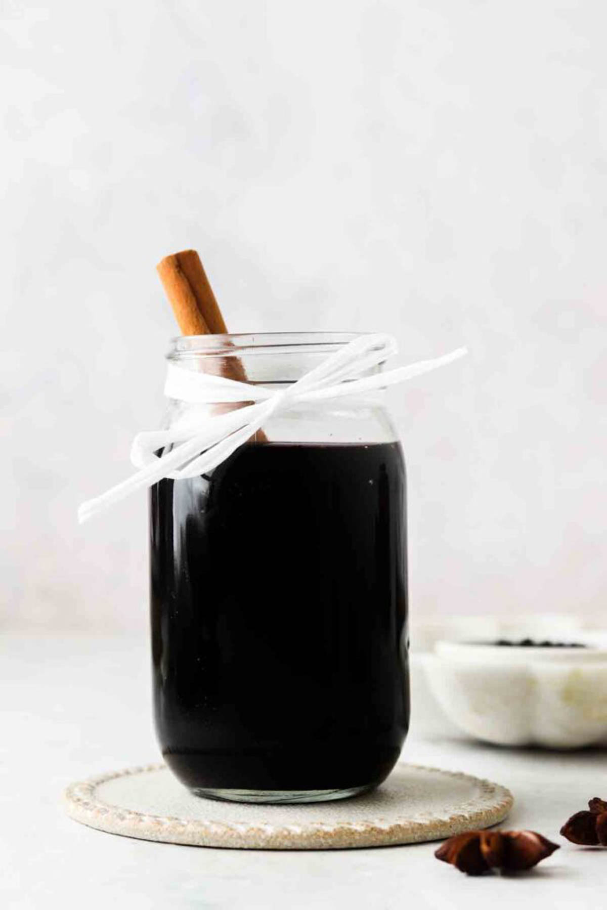 Homemade elderberry syrup in a glass mason jar with a white bow.