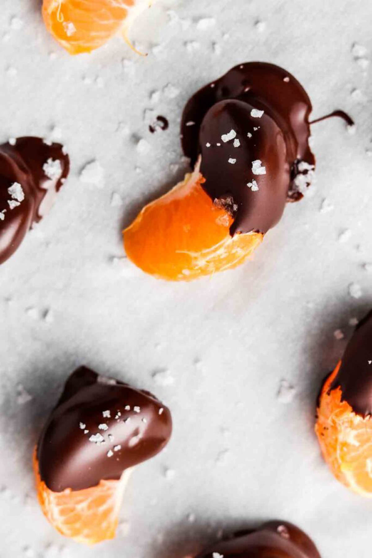 Chocolate covered oranges on a baking sheet with salt sprinkled on top.