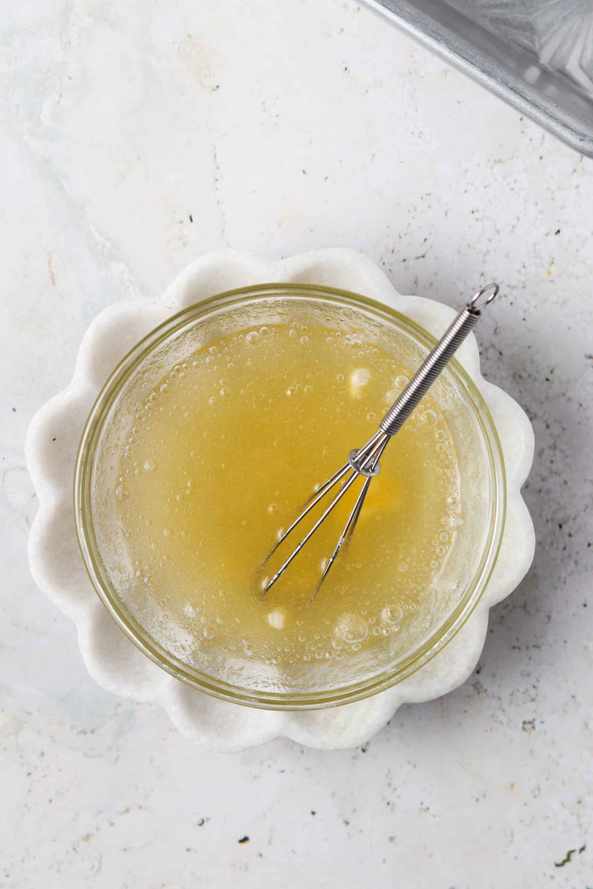 AIP gelatin egg in a small glass bowl on a cream plate with a small whisk in the bowl.