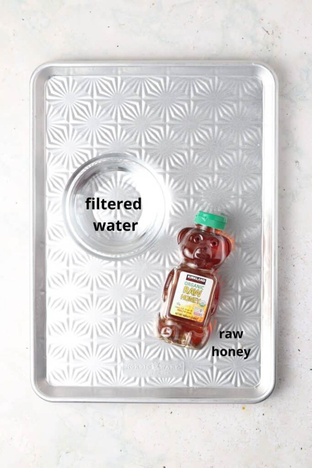 Honey simple syrup ingredients in a small glass bowl on a silver tray. 