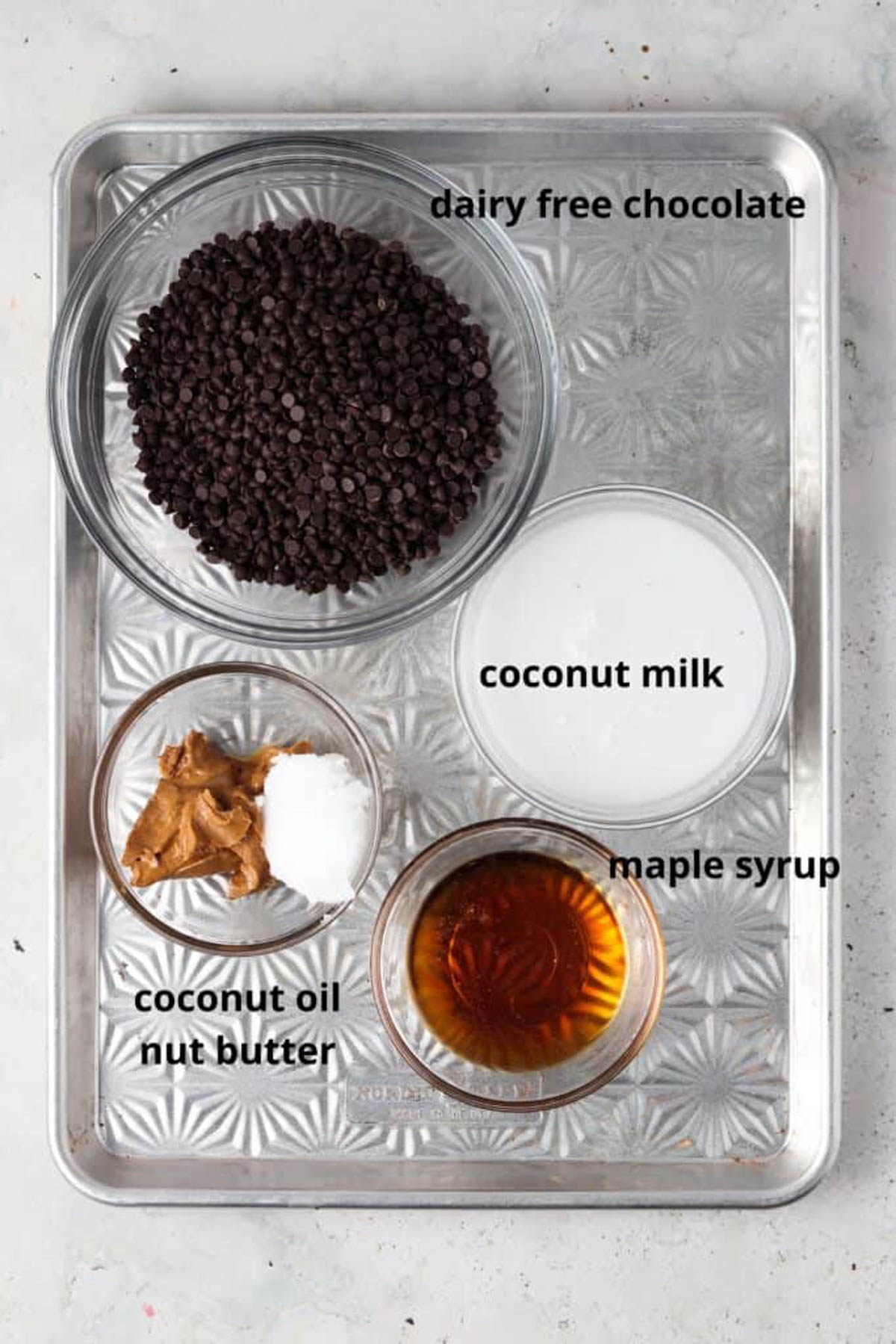 Vegan chocolate truffle ingredients in small glass bowls on a silver tray.