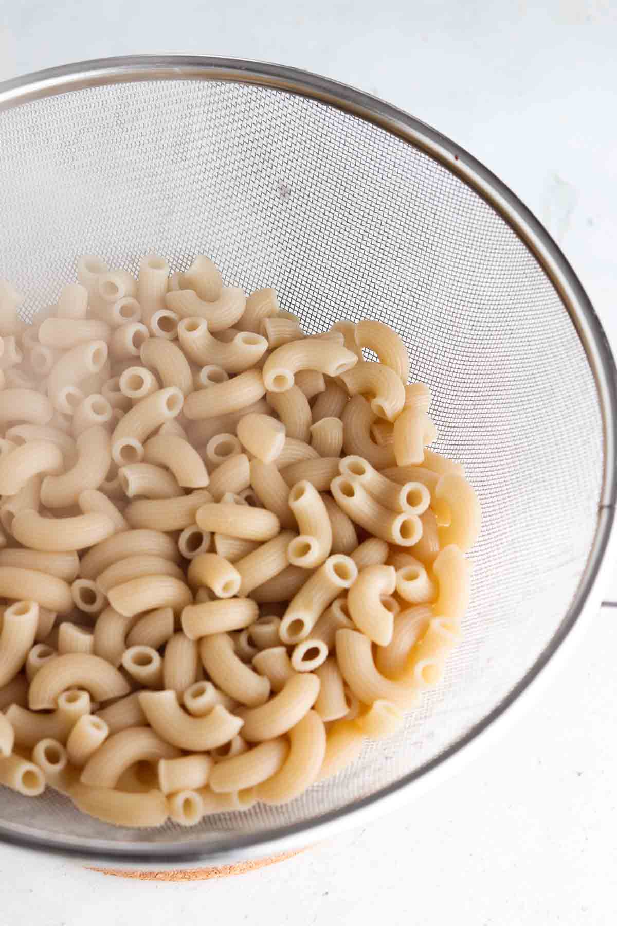 Noodles being strained in a colander. 