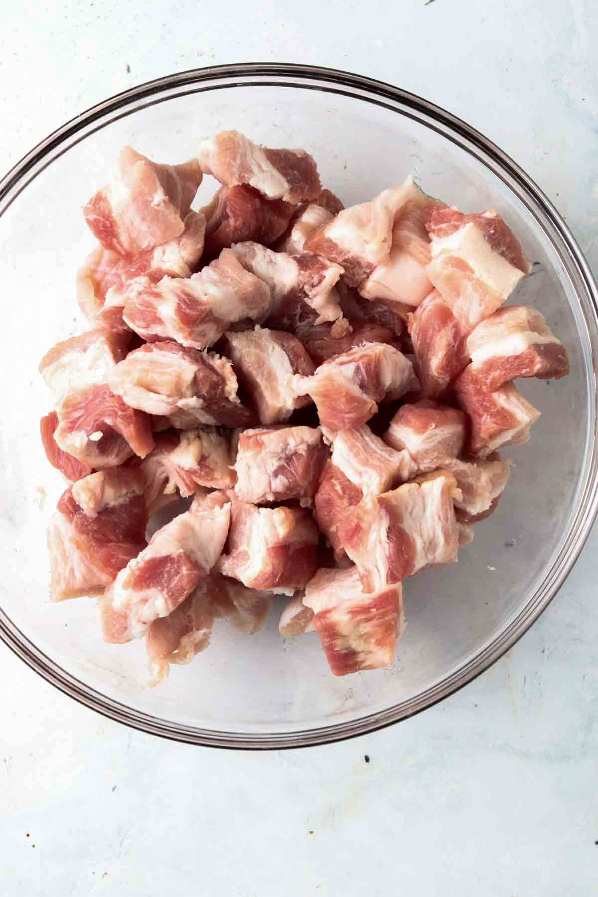 1 inch cubes of pork belly in a glass bowl.