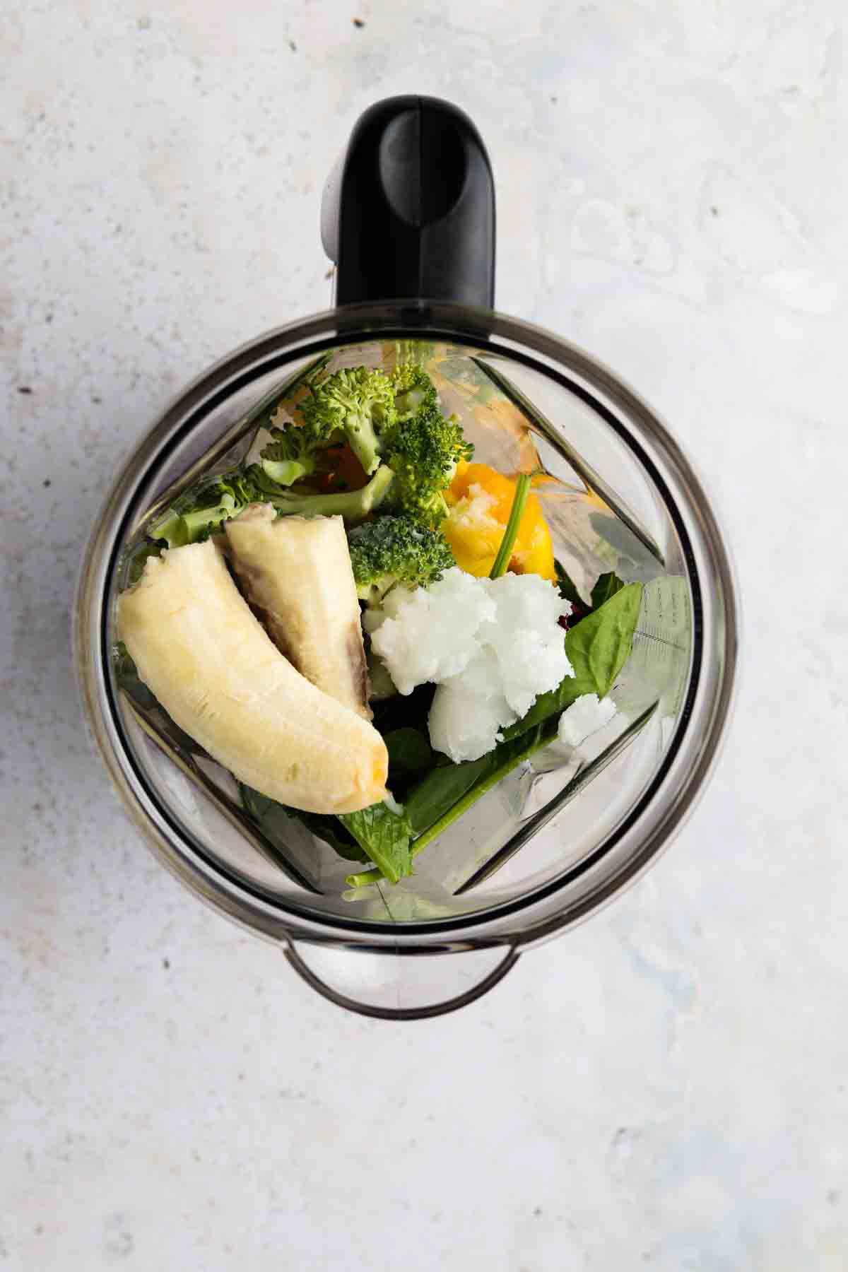 Coconut oil, collagen peptides, frozen pineapple, coconut milk, banana, spinach, and broccoli florets all in a blender.